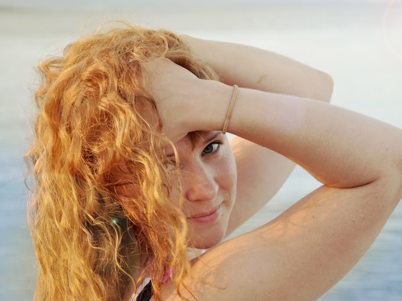 Frau mit roten Haaren streicht sich durch die Haare