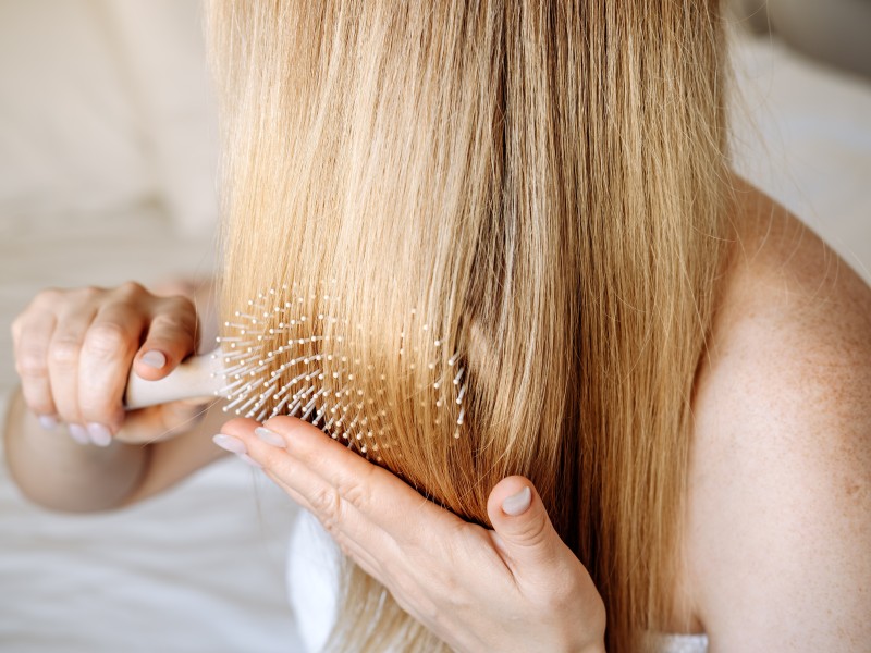 Frau kämt durch ihren langen blonden Haare