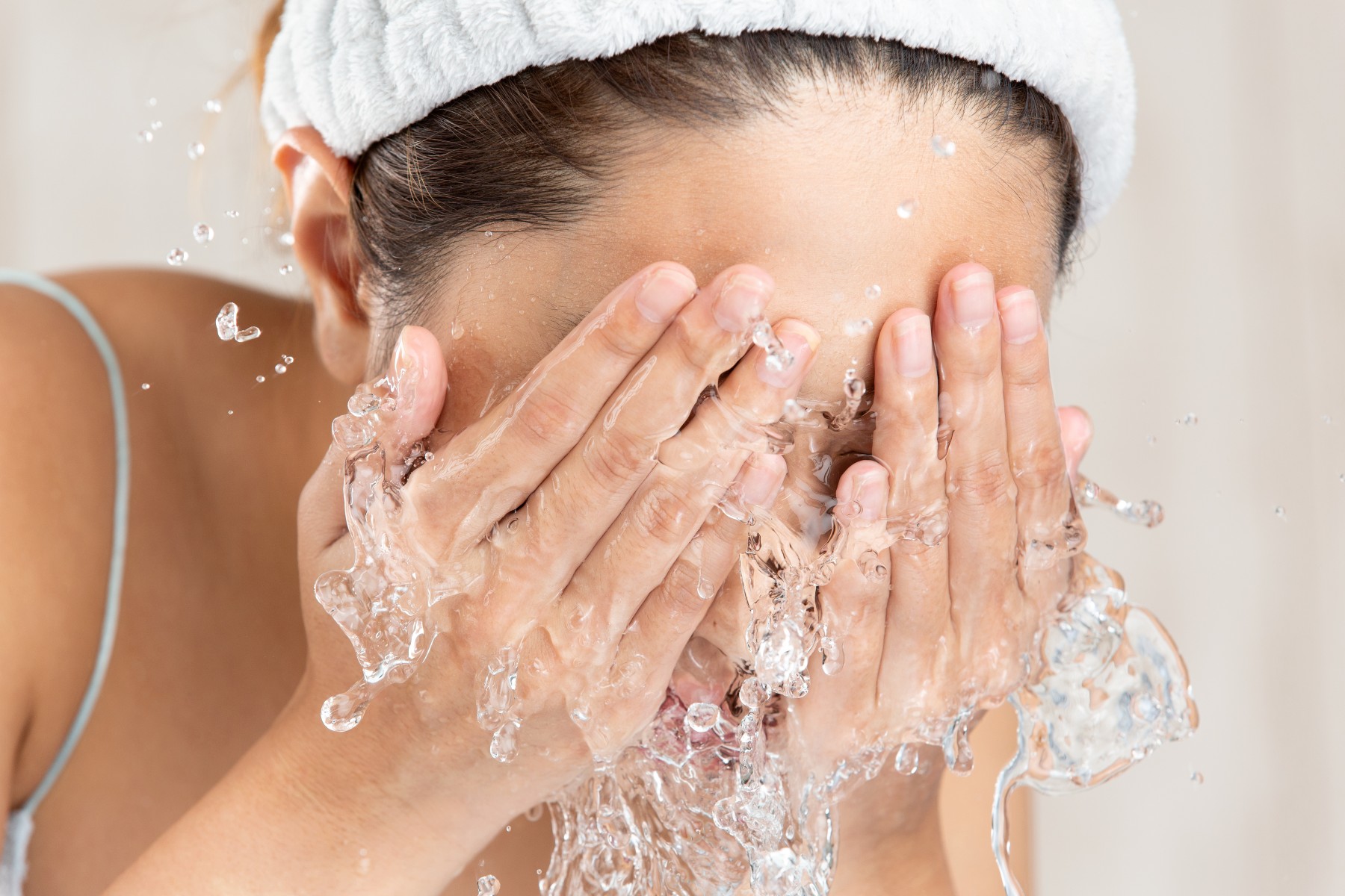 Frau wirft sich Wasser ins Gesicht über einem Lavabo