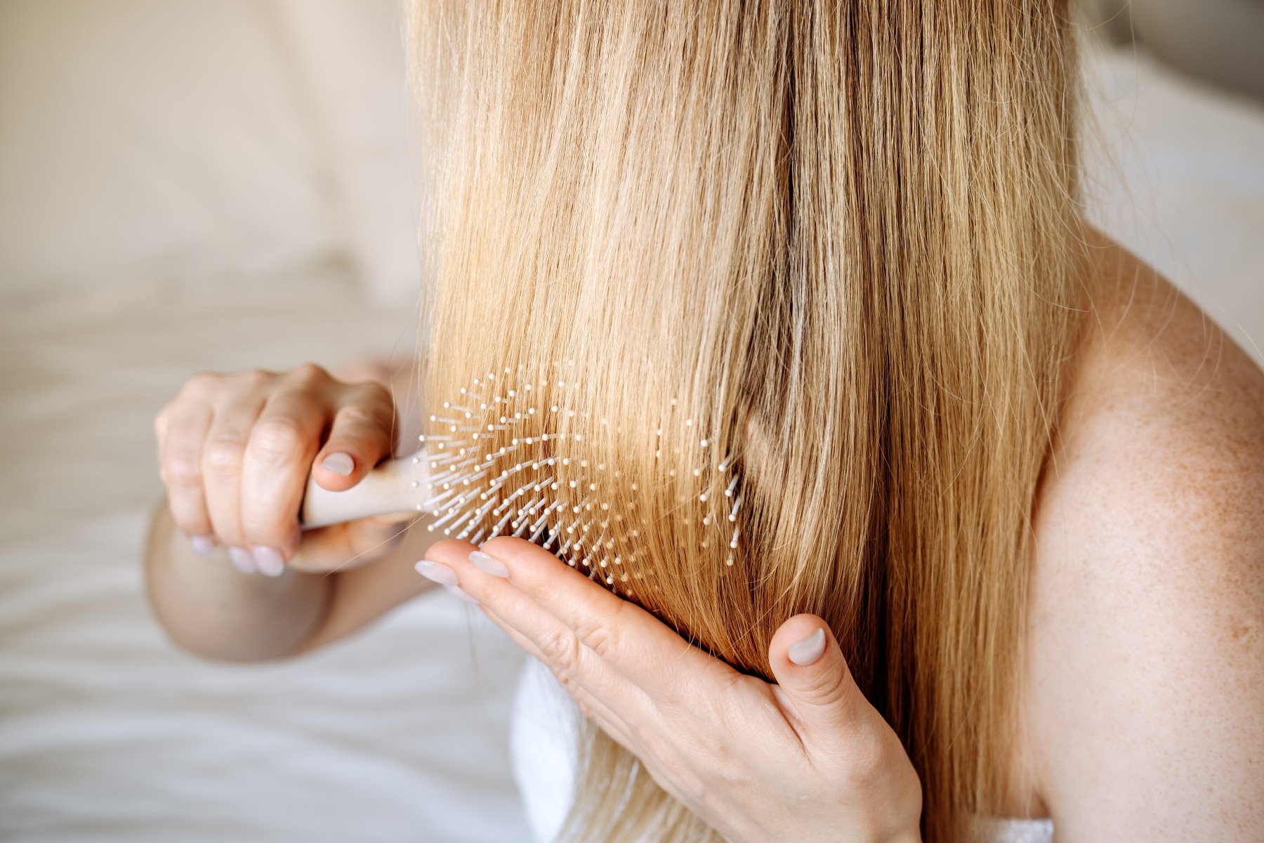 Frau kämt sich durch ihre langen blonden Haare