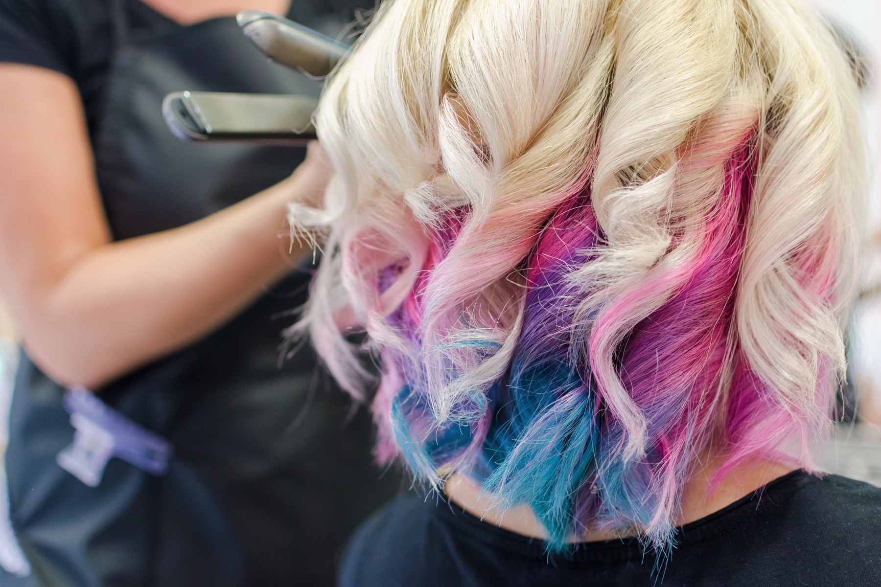 Frau bei Hairstylistin. Frau hat weisse Haare mit verschieden farbigen Locken.